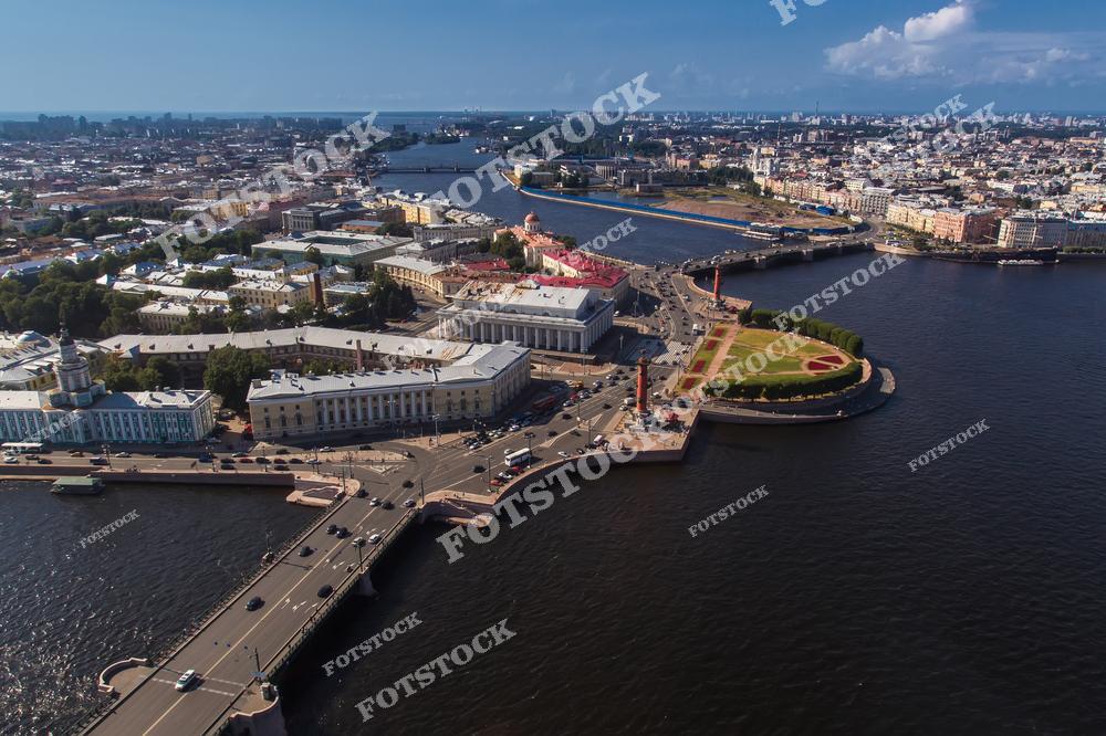 Панорамный вид на Васильевский остров и Санкт-Петербург с высоты птичьего полёта в ясный летний день. Аэрофотосъёмка из кабины вертолёта открывает масштабный городской пейзаж северной столицы России с её исторической архитектурой, набережными Невы и современной городской инфраструктурой. Фотография передаёт атмосферу большого европейского города, красоту исторического центра и уникальные виды Санкт-Петербурга с воздуха. Изображение идеально подходит для публикаций о путешествиях по России, городской архитектуре, туризме, аэрофотосъёмке и панорамах Петербурга.
